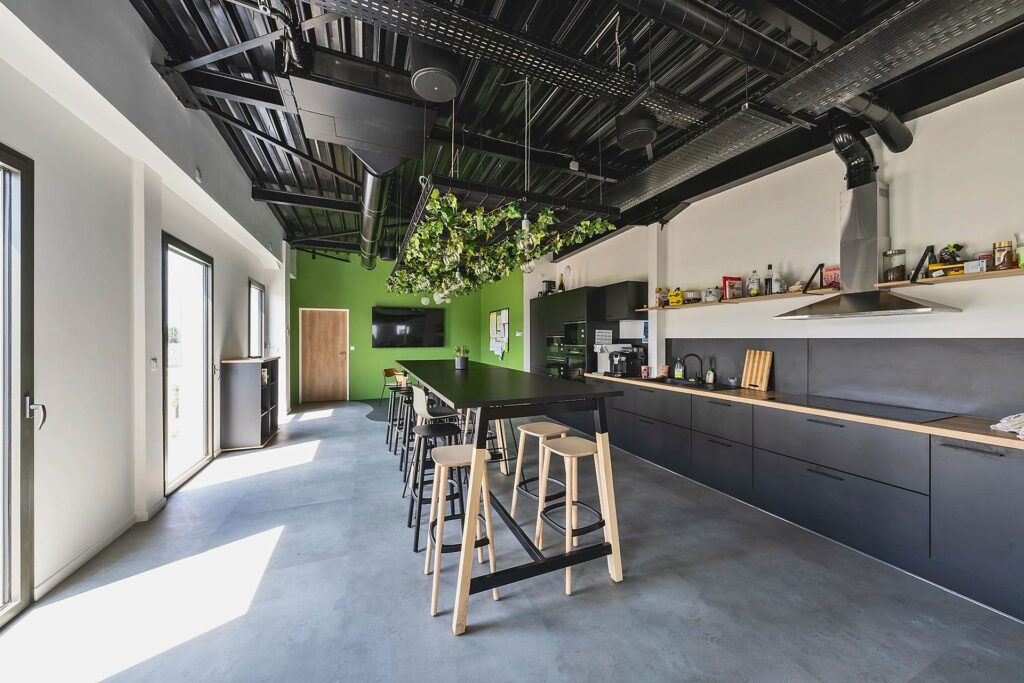 Cuisine et espace pause des bureaux Explorair, plafond technique apparent, à Chasse-sur-Rhône