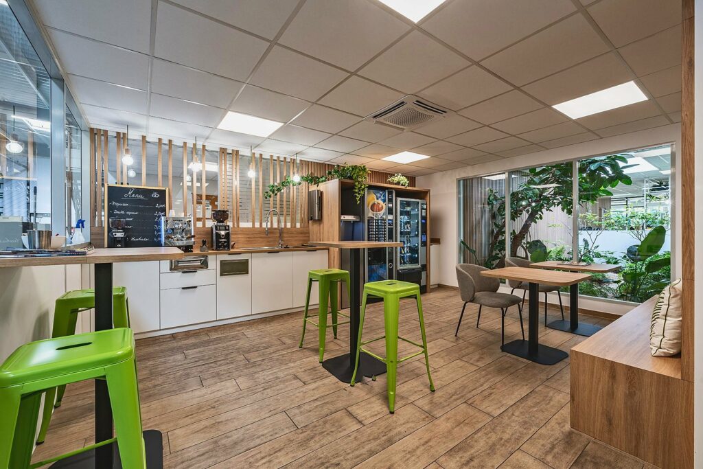 Espace café avec tabourets verts et cloisons bois au siège de Santos, à Vaulx-en-Velin